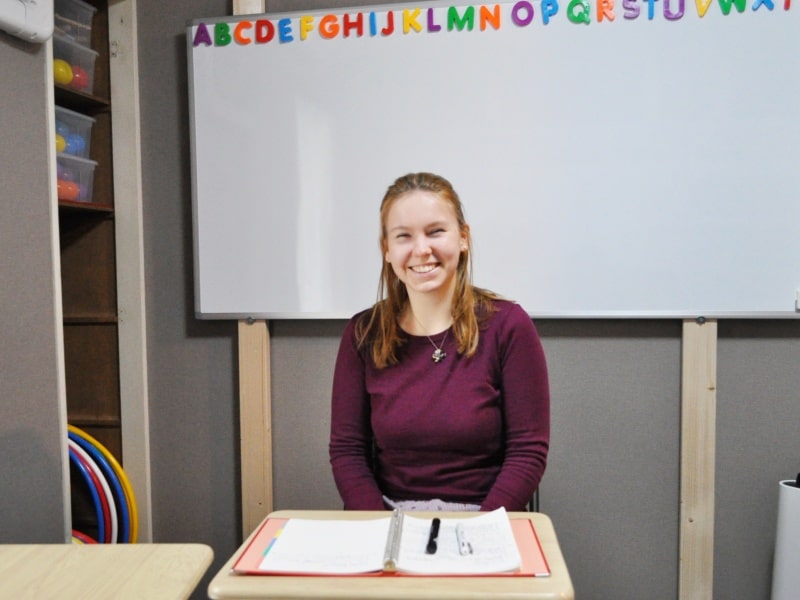 ２０２２年の２月、福岡市早良区にあるWeltドイツ語教室・室見教室のホワイトボードの前に座っている、当教室の先生の写真